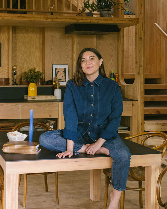 Shana Rehwald sits on a table with a stack of Me-est Me Journals next to her. 